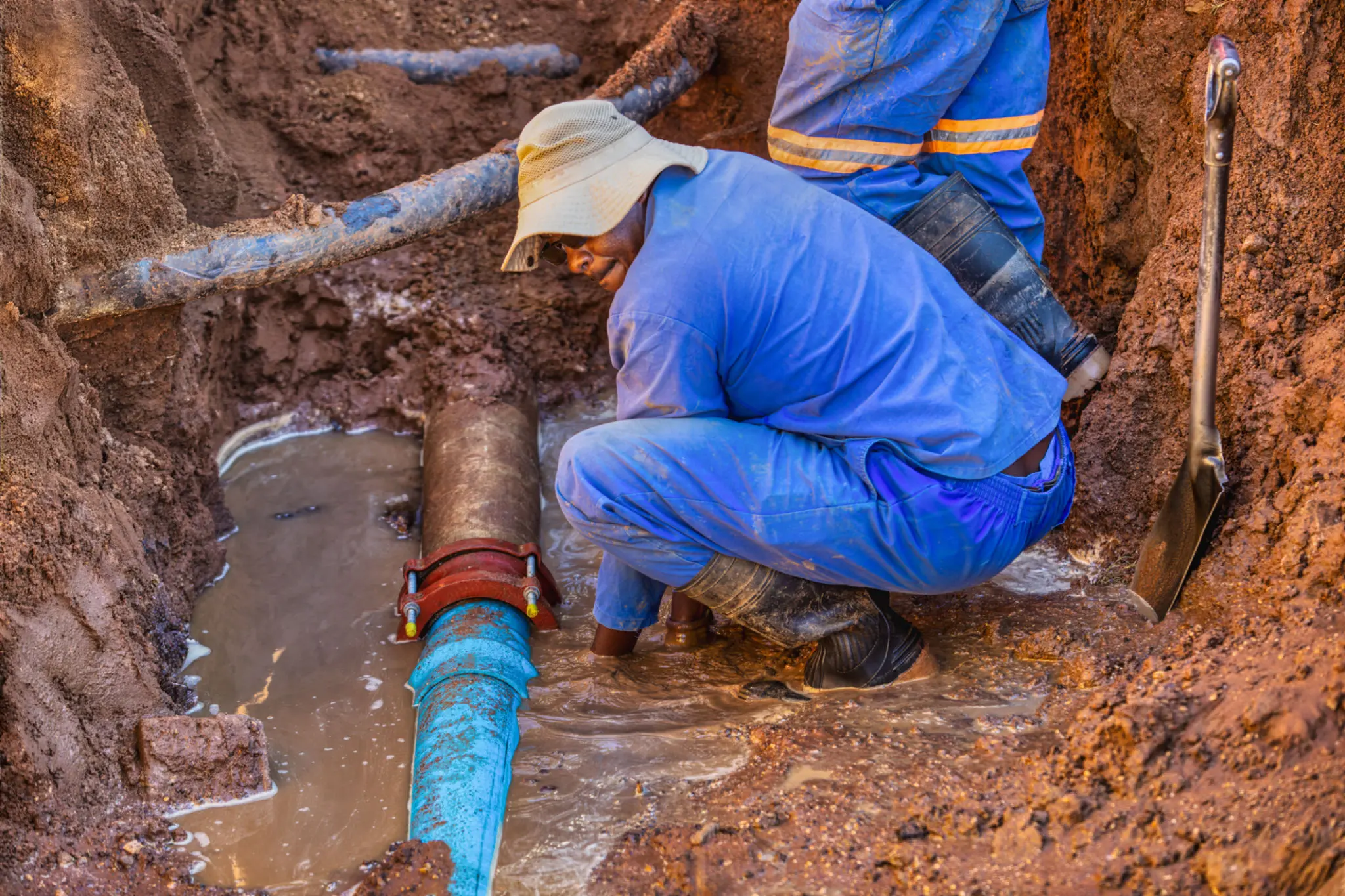 Workers repairing a water pipe underground.